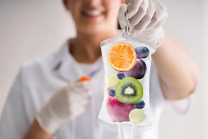 Eine Mitarbeiterin hat einen symbolischen Infussionsbeutel mit Obst in der Hand.