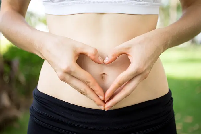 Mikrobiologische Therapie. Eine Frau hält sich den Bauch.
